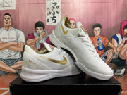 Angled view of white and gold Nike Kobe basketball shoes