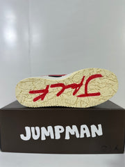 Outsole view showing the textured off-white tread with red graphic accents, positioned above a Jumpman Jack box.