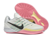 Side view of a pale Nike Kobe basketball shoe with a black Swoosh, turquoise side accents, and a pink patterned outsole.