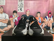 Front view of black Nike basketball sneakers with white swooshes, silver-gray sides, and black laces.