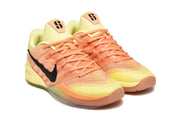 Pair of yellow and orange Nike Kobe basketball shoes in a three-quarter view.