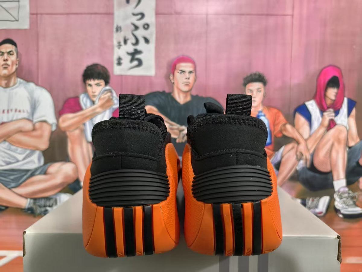 Rear view of black and orange sneakers showing ribbed black heel panels and orange-and-black vertical outsole details.