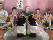 Front view of pink Jordan basketball shoes with black laces and orange and pink tongue details.