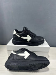 Pair of black and white low-top sneakers shown from the side and outsole, highlighting the white arrow detail and textured black tread.