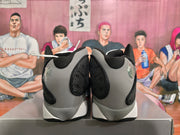 Rear view of black and grey high-top basketball sneakers with white midsoles on a shoebox.