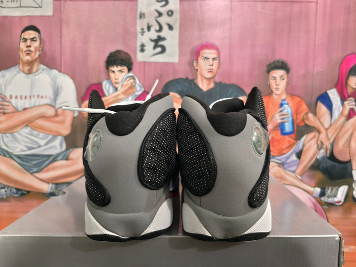 Rear view of black and grey high-top basketball sneakers with white midsoles on a shoebox.