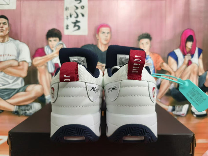 Rear view of white Jordan shoes with navy soles and red heel pull tabs.