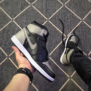 Side view of a single black and grey high-top sneaker held above the patterned floor.