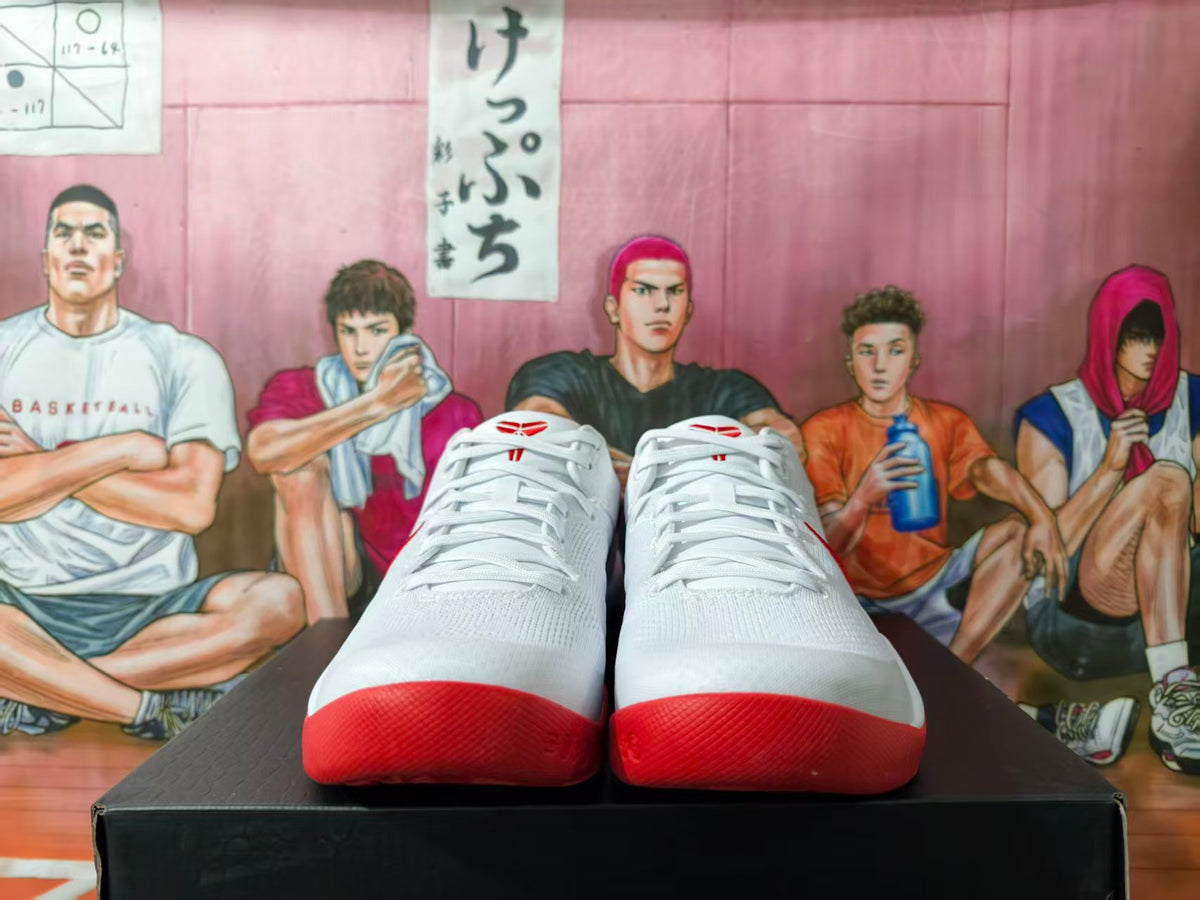 Front view of white Nike basketball shoes with red toe and outsole accents.