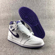 Angled view of the sneakers with one shoe lifted to show the purple outsole pattern and perforated toe box.