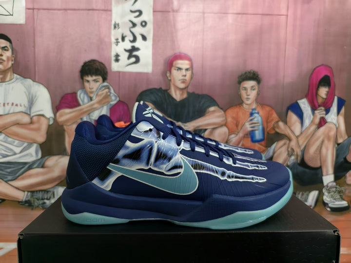 Side view of navy Nike basketball sneakers with a skeletal X-ray graphic, pale blue-green accents, and a translucent-looking outsole.
