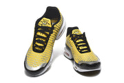 Top and front views of yellow patterned Nike Air Max Plus sneakers with black laces.