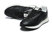 Pair of black lace-up low-top sneakers with white collar lining and contrast midsoles.