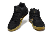 Pair of black sneakers shown from the front with gold branding details and textured uppers.