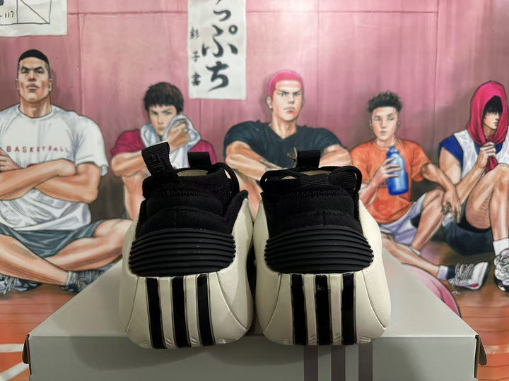 Pair of black and white low-top sneakers viewed from the heel, with red accents partially visible and a graphic sports-themed background.
