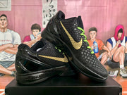 Angled view of black Kobe basketball shoes showing gold logos and textured uppers