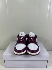 Front view of the burgundy and white sneakers with perforated toe boxes and Jordan tongue logos.