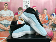 Angled view of the blue-gray and black Jordan shoes showing the side panels, white midsoles, and turquoise heel branding.