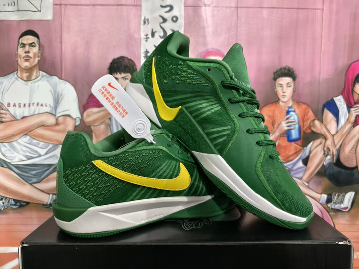 Pair of green Nike basketball sneakers with yellow Swoosh branding displayed on a black shoebox.