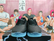Front view of the black basketball sneakers with black laces, textured toe boxes, and blue translucent outsoles.