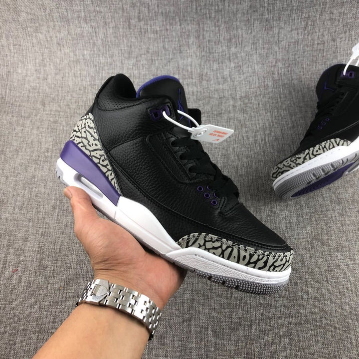 Close-up angled view of black Jordan 3 sneakers with purple accents and elephant-print toe and heel panels.