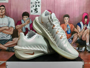 Angled view of the white basketball shoes with bronze-colored accents and sculpted sides