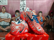 Pair of orange and white Nike basketball sneakers with blue laces and a patterned upper displayed on an orange shoebox.