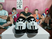 Rear view of the sneakers showing contrasting heel details, including GIGI lettering on one shoe and the number 2 on the other.