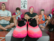 Front view of pink and black Nike basketball sneakers with black laces, layered pink panels, and textured toe areas.