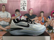 Side profile of a light blue-gray Nike basketball sneaker with black laces and layered heel details.