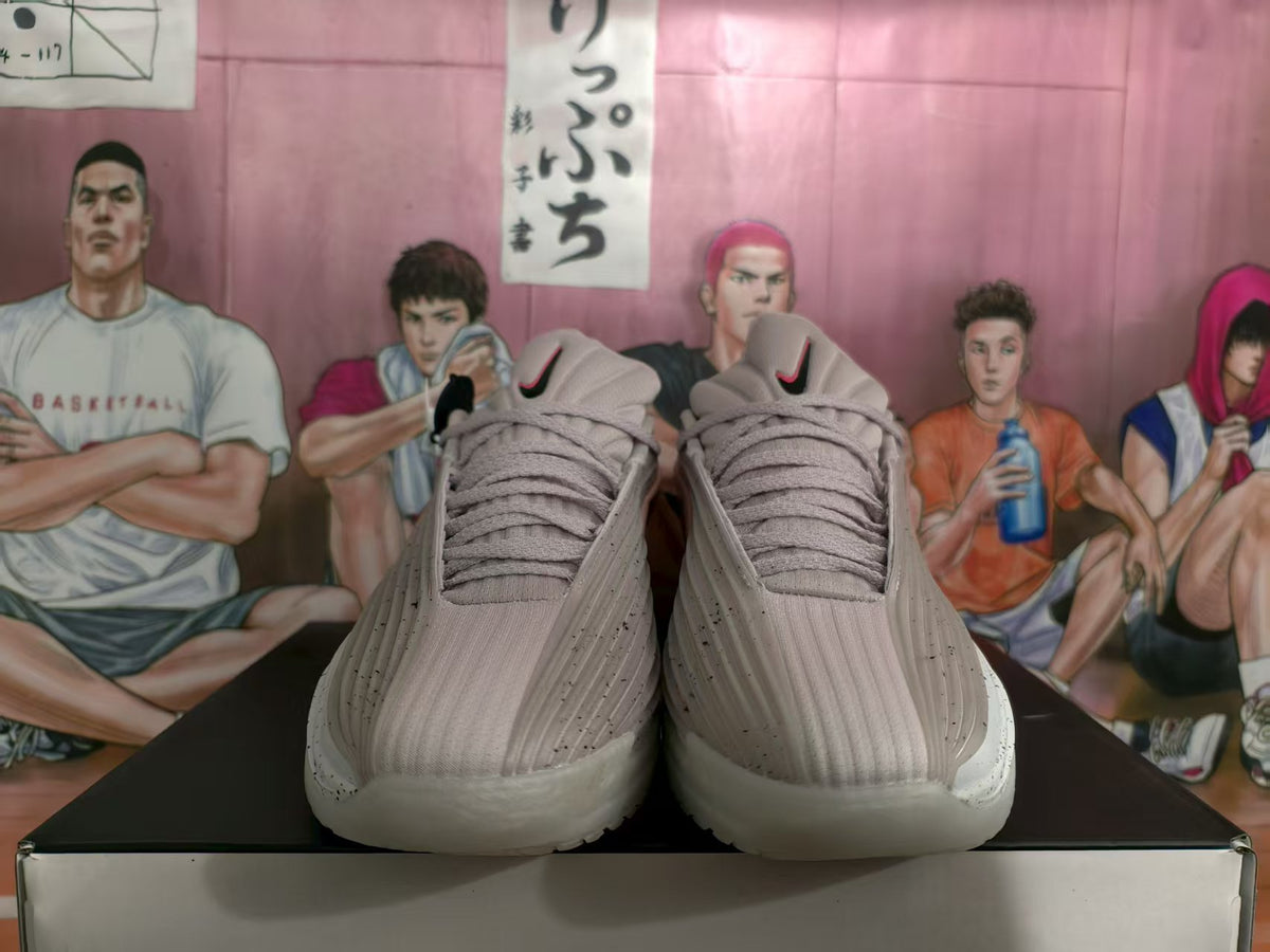 Front view of gray and pink Nike basketball sneakers with layered uppers and white speckled soles.