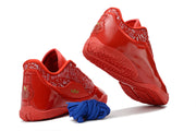 Red Nike LeBron 23 basketball shoes shown from the rear and outsole with blue alternate laces.