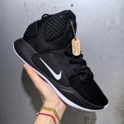 Side view of the black Nike sneaker showing the white Swoosh, textured upper, padded collar, and black midsole.