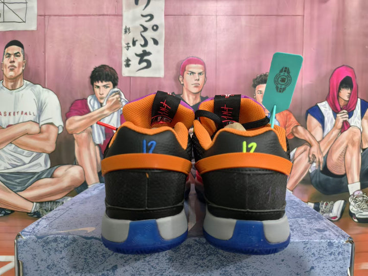 Rear view of black and orange basketball shoes with blue accents and contrasting heel details.
