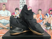 Black Nike basketball sneakers shown from an angled side view with multiple straps and white Swoosh detailing