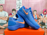 Angled view of blue Nike sneakers with orange Swoosh logos and ribbed soles.