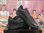 Black lace-up basketball sneakers displayed at an angled side view, showing the padded collar and layered upper.