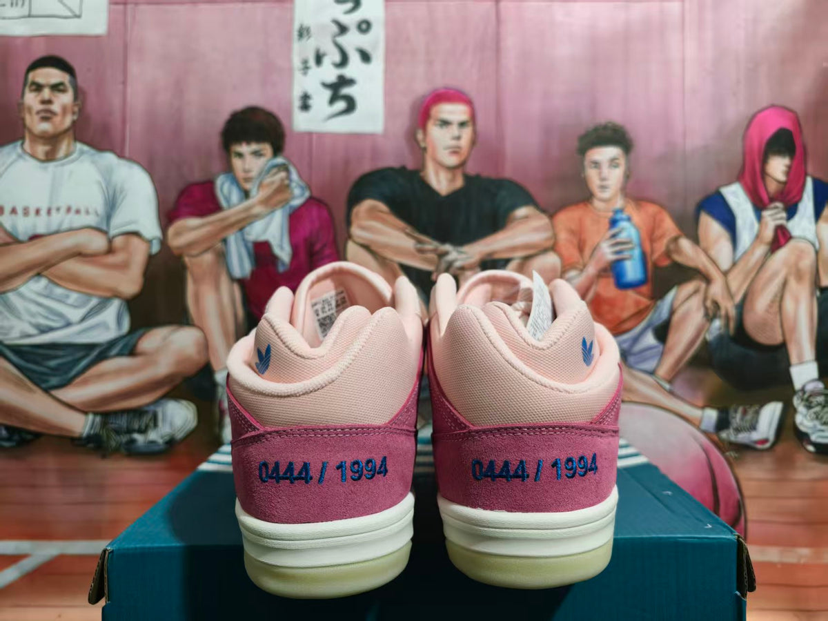 Rear view of pink and burgundy low-top adidas sneakers showing heel graphics and cream-colored soles