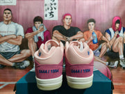 Rear view of pink and burgundy low-top adidas sneakers showing heel graphics and cream-colored soles