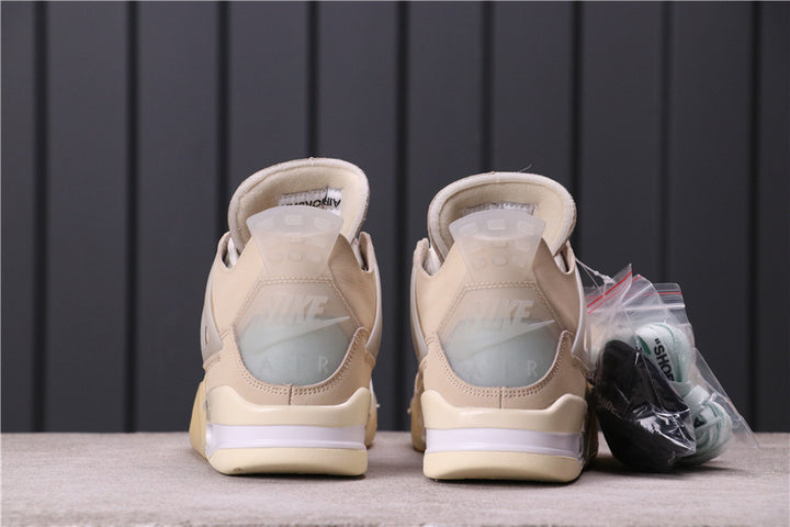 Rear view of a pair of cream and off-white Jordan 4 style sneakers with translucent heel details and additional laces in packaging.
