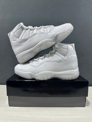 Two white high-top sneakers arranged on a black shoebox, showing side and outsole details.