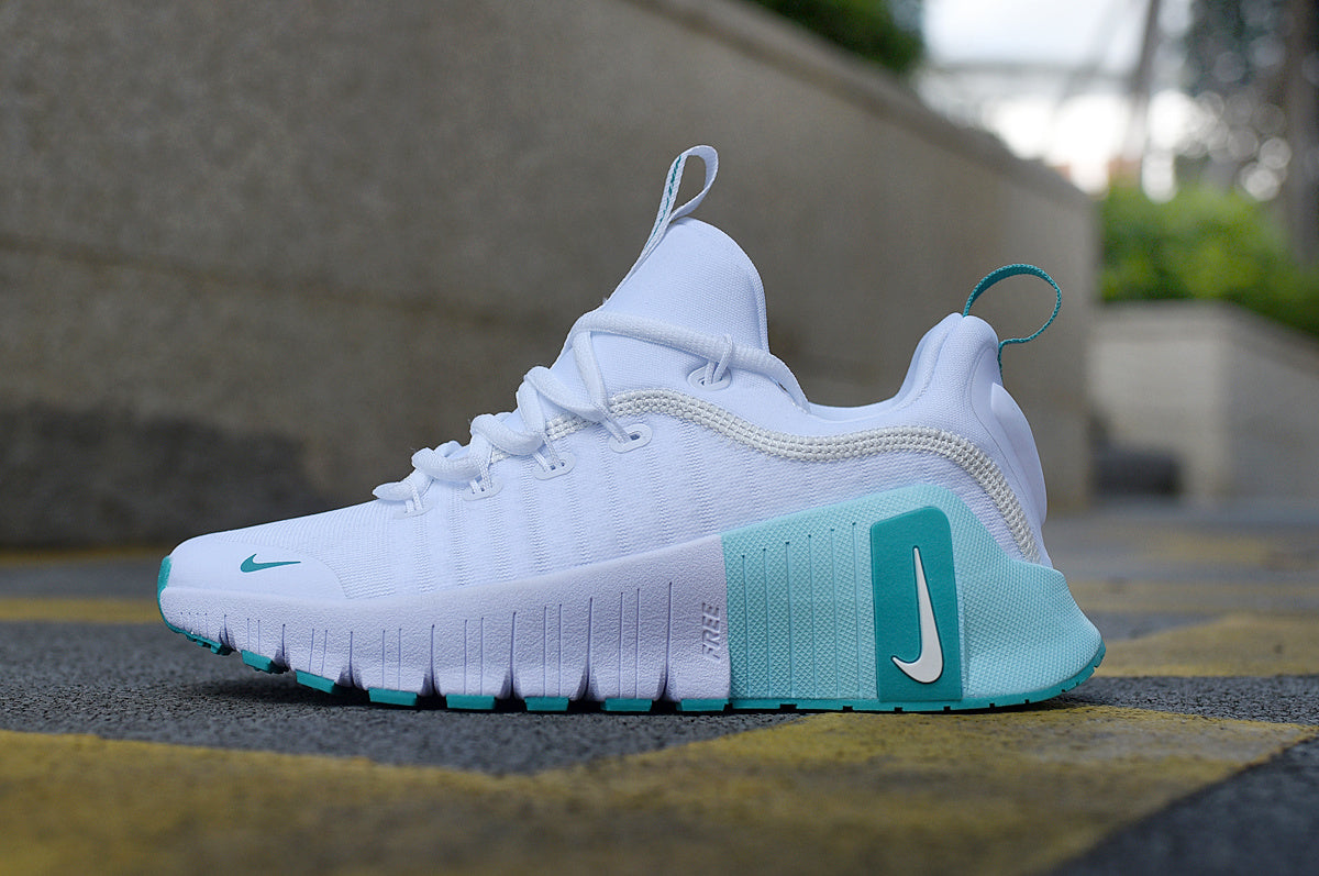 Side view of a white Nike low-top sneaker with teal accents and a sculpted sole.