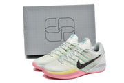 Pair of pale Nike Kobe basketball shoes beside a gray box, showing the black Swoosh and multicolor sole accents.