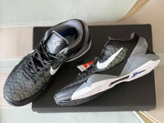 Pair of Nike Kobe 7 sneakers displayed on a black shoebox, showing the patterned uppers and geometric midsoles.