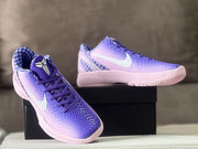 Three-quarter view of the sneakers showing the Kobe tongue emblem, purple laces, textured toe box, and checkerboard lining.