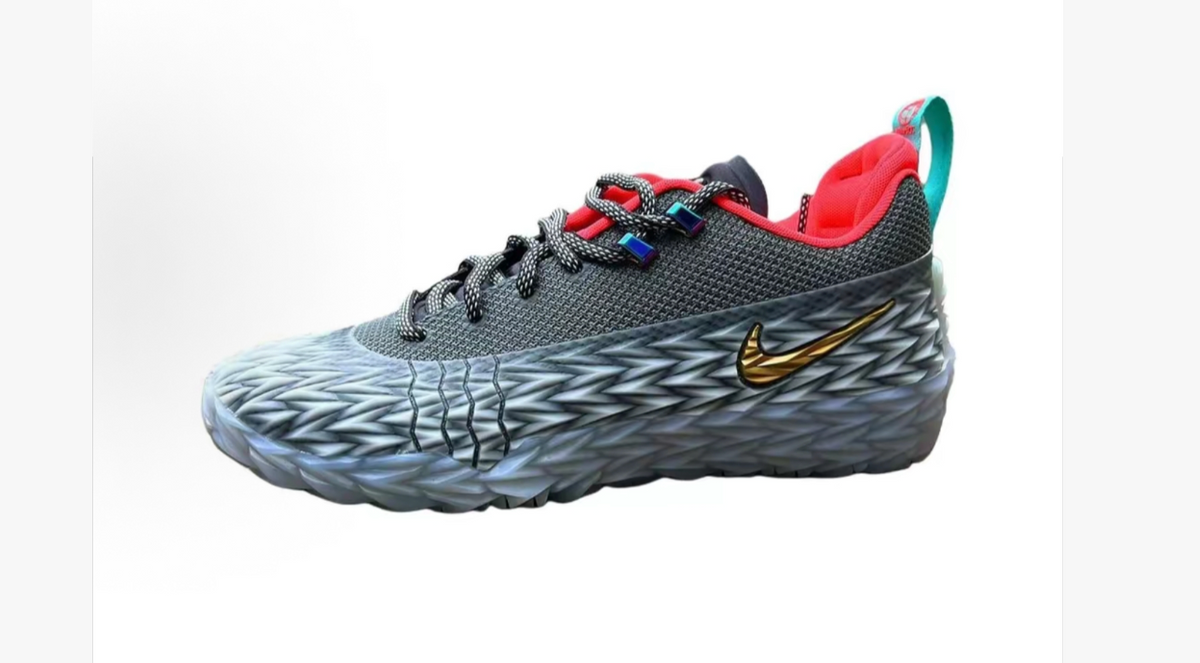 Gray low-top sneaker with a textured upper, gold-tone Swoosh, red collar lining, teal heel accent, and patterned sole