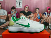 Side profile of a white Nike sneaker with green accents