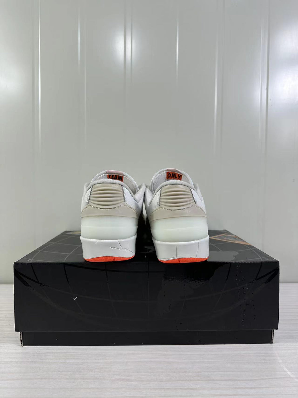 Rear view of the beige and white low-top sneakers showing ribbed heel details and orange outsole accents.