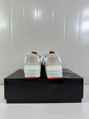 Rear view of the beige and white low-top sneakers showing ribbed heel details and orange outsole accents.