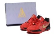 Pair of red, black, and gold basketball shoes beside a branded box